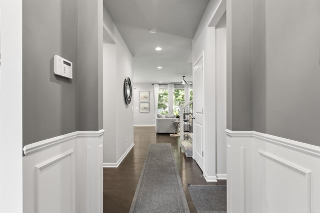 hall featuring a wainscoted wall, recessed lighting, and dark wood-type flooring