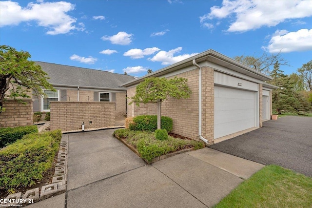 view of home's exterior featuring brick siding, an attached garage, and driveway