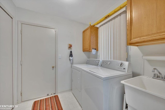 clothes washing area with a sink, cabinet space, and washer and dryer
