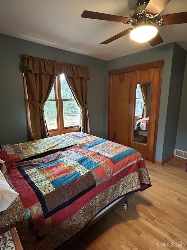 bedroom featuring ceiling fan, visible vents, multiple windows, and light wood-type flooring