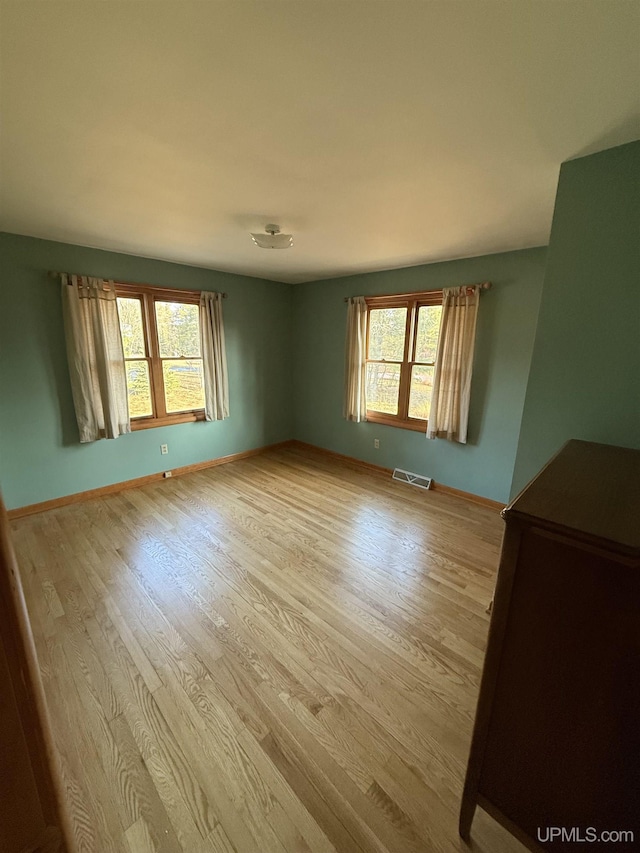 spare room featuring baseboards, visible vents, and light wood-style floors