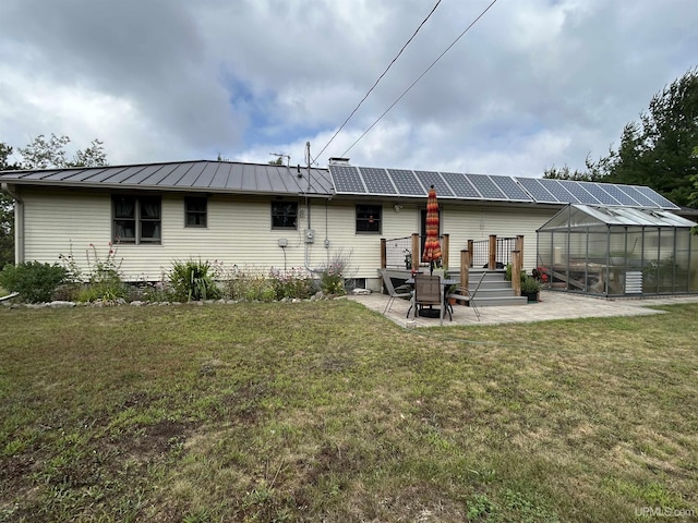 rear view of property featuring a standing seam roof, a yard, an exterior structure, and a patio area