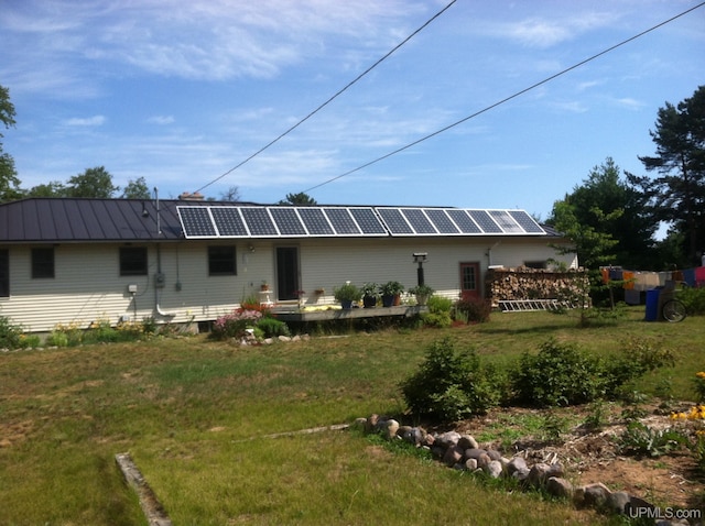 back of property with a lawn and solar panels
