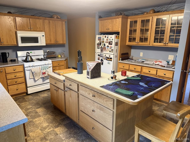 kitchen with white appliances, light countertops, a center island, a kitchen bar, and glass insert cabinets