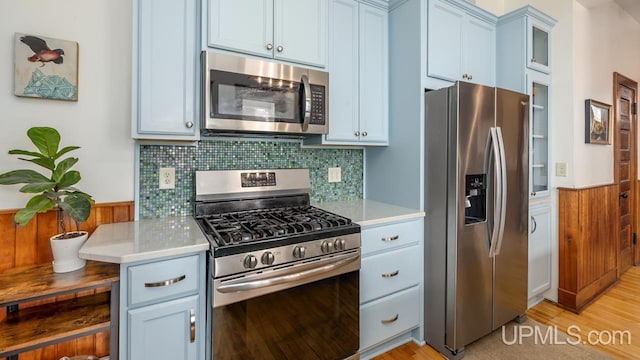 kitchen with light countertops, appliances with stainless steel finishes, and a wainscoted wall