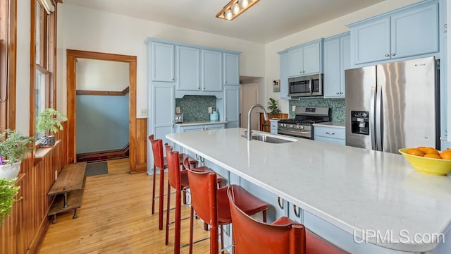 kitchen with backsplash, blue cabinetry, appliances with stainless steel finishes, and a sink