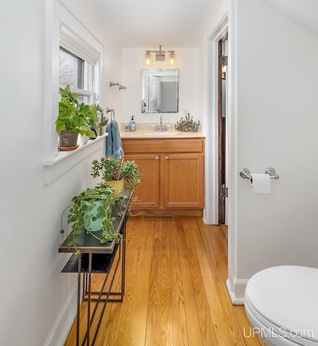 bathroom featuring vanity, baseboards, toilet, and wood finished floors