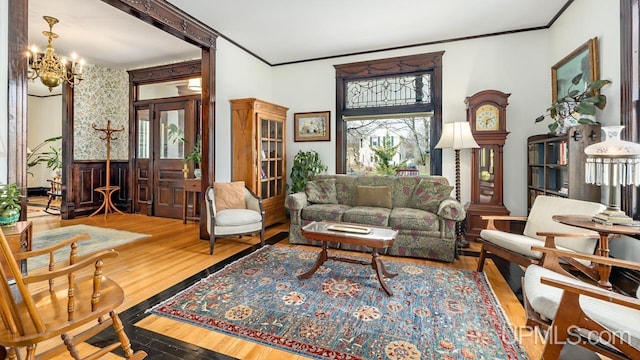 sitting room with an inviting chandelier, ornamental molding, and wood finished floors