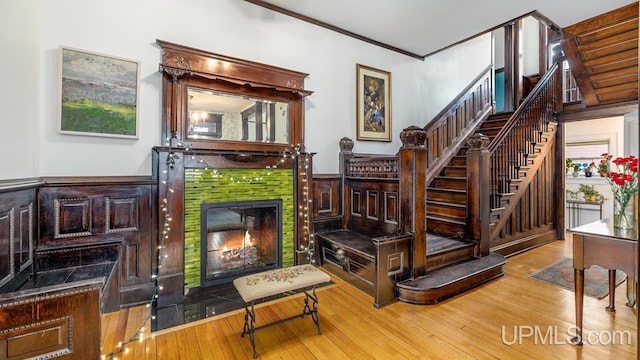 interior space featuring crown molding, stairway, hardwood / wood-style flooring, and a tile fireplace