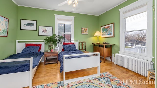 bedroom with radiator heating unit, crown molding, wood finished floors, and ceiling fan