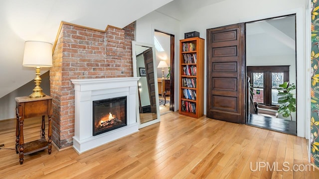 living room featuring a glass covered fireplace, vaulted ceiling, and hardwood / wood-style floors