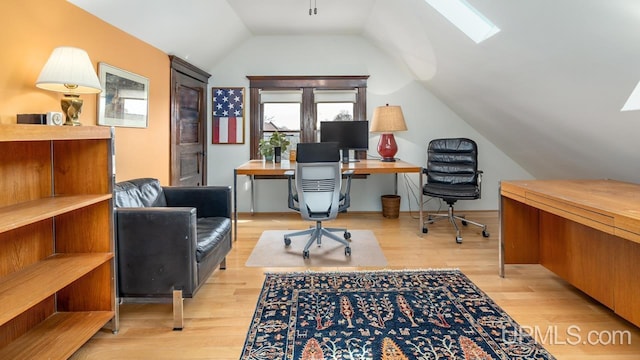 office featuring light wood-type flooring and lofted ceiling with skylight