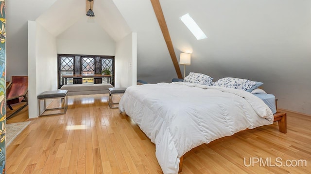 bedroom featuring light wood finished floors and vaulted ceiling with skylight