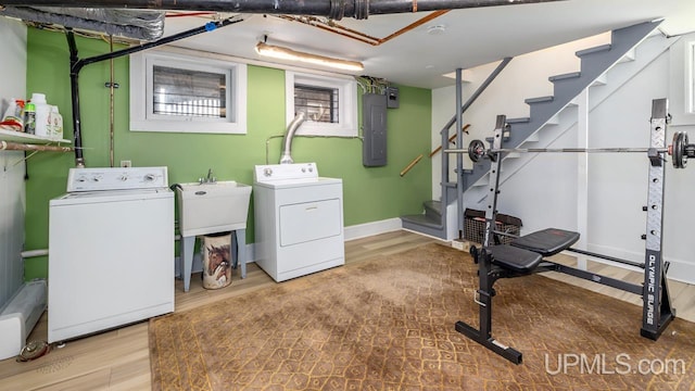 laundry area featuring laundry area, wood finished floors, baseboards, electric panel, and independent washer and dryer