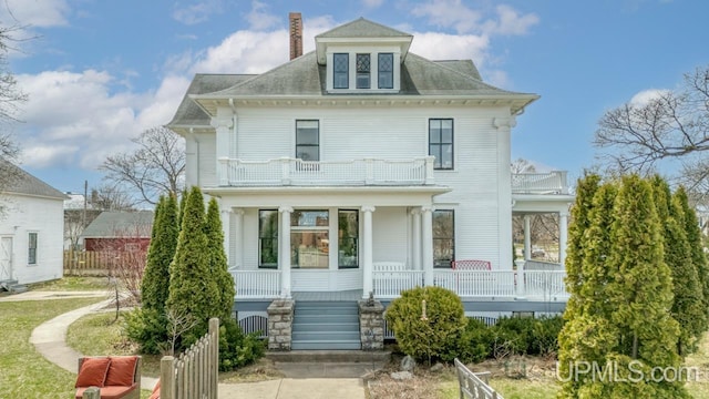 back of house featuring fence, a chimney, a porch, and a balcony