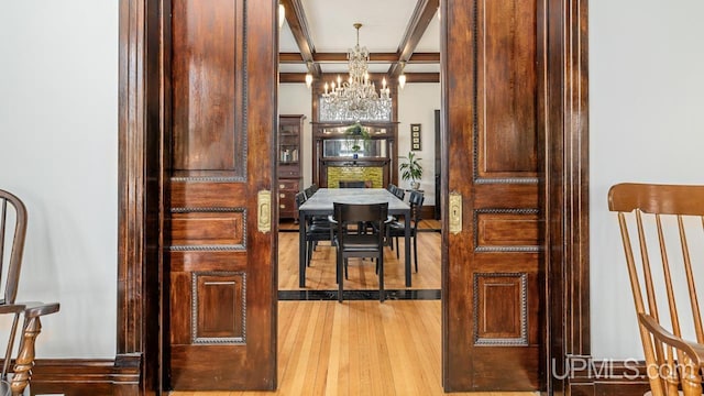 dining room with wood finished floors, a chandelier, beam ceiling, and coffered ceiling
