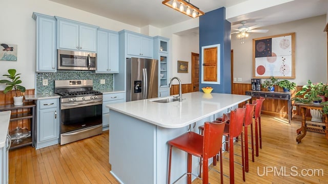 kitchen featuring a sink, light countertops, a kitchen breakfast bar, light wood-style flooring, and stainless steel appliances