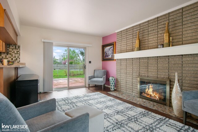 living area with baseboards, a brick fireplace, and wood finished floors