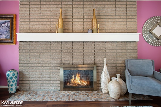 interior details featuring a brick fireplace, baseboards, and wood finished floors