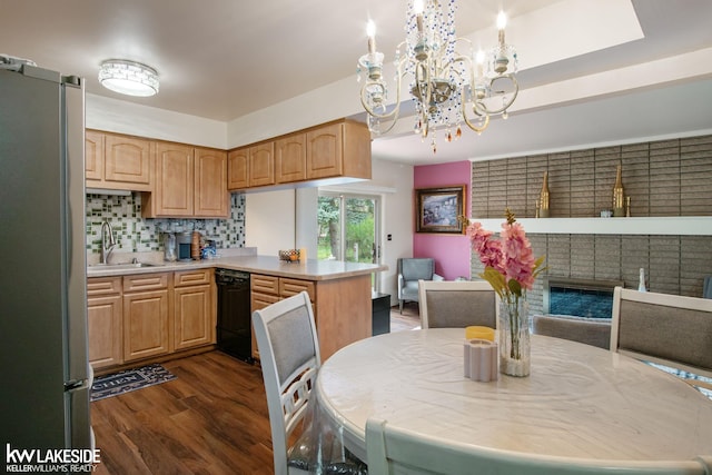 kitchen featuring freestanding refrigerator, dark wood-style flooring, a peninsula, black dishwasher, and a sink