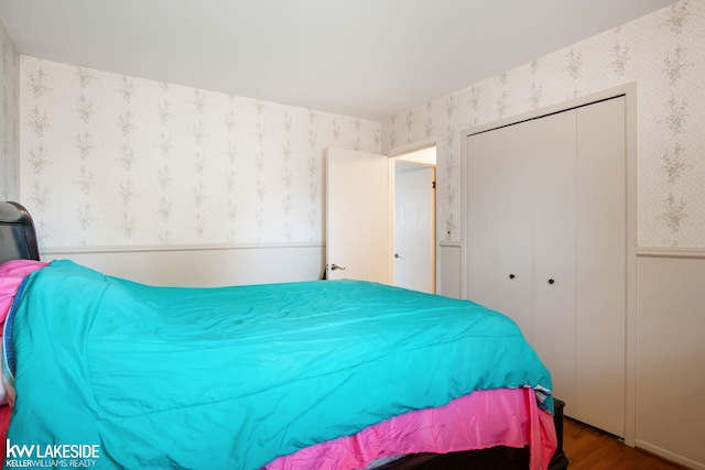 bedroom with a closet, wood finished floors, and wallpapered walls