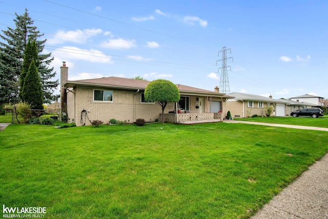 ranch-style home featuring a front yard, a chimney, brick siding, an attached garage, and driveway