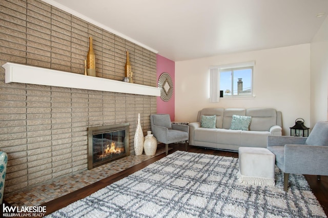 living area with a brick fireplace and wood finished floors