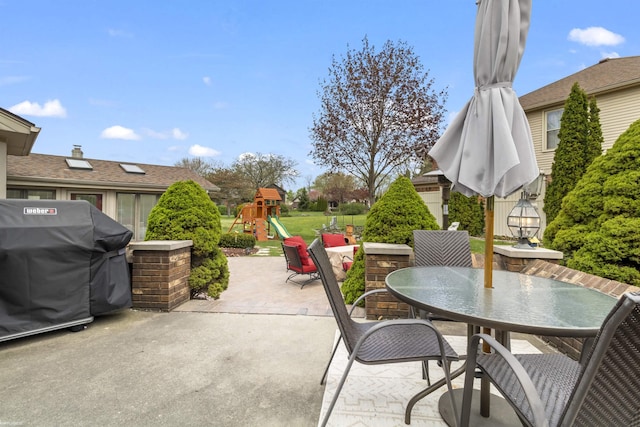 view of patio / terrace with a playground, outdoor dining space, and a grill