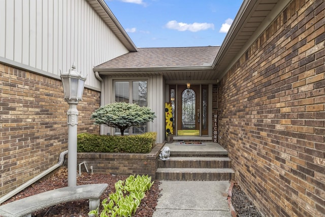 property entrance featuring board and batten siding, brick siding, and a shingled roof