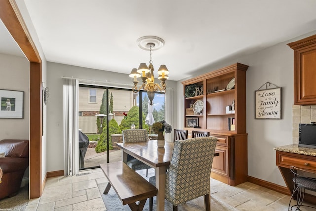 dining room with baseboards, stone tile floors, and a notable chandelier