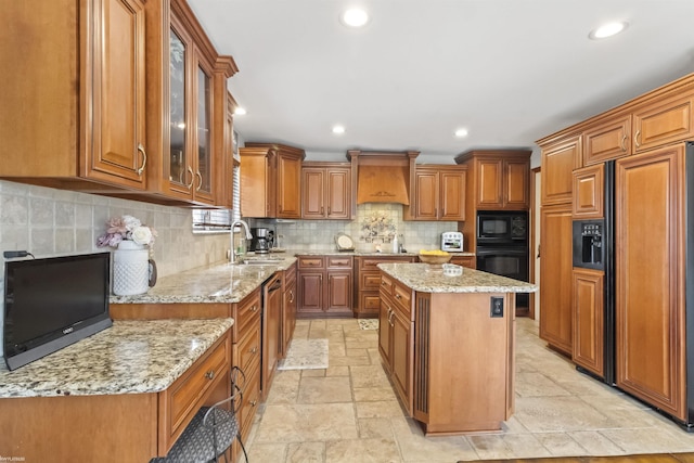 kitchen featuring brown cabinets, a center island, stone tile floors, tasteful backsplash, and black appliances