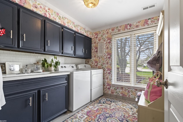 washroom with cabinet space, a sink, baseboards, separate washer and dryer, and wallpapered walls