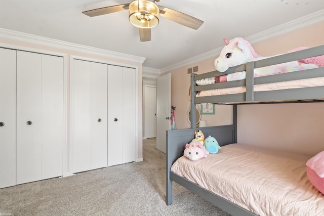 bedroom with crown molding, visible vents, two closets, ceiling fan, and light colored carpet