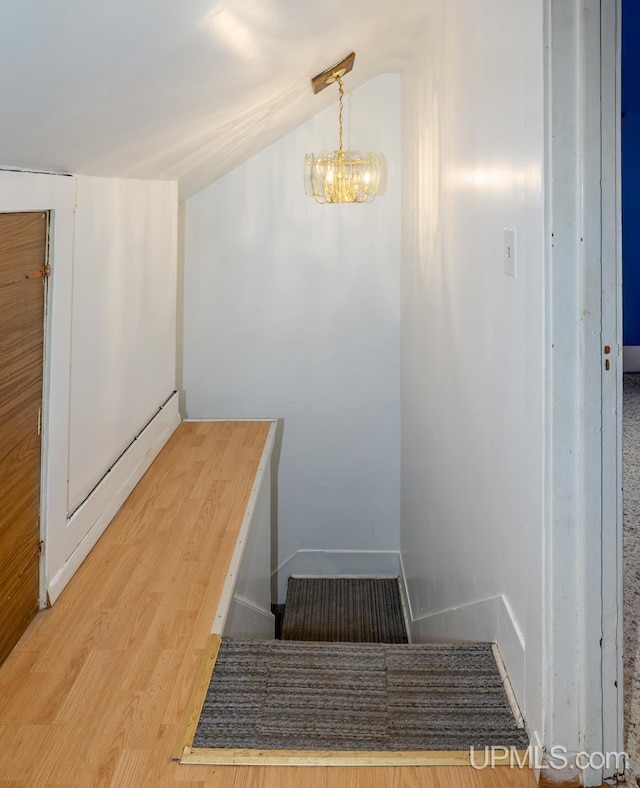stairway featuring wood finished floors and a chandelier