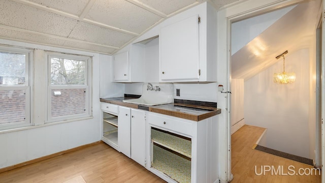 kitchen featuring light wood-style floors, white cabinetry, lofted ceiling, and dark countertops