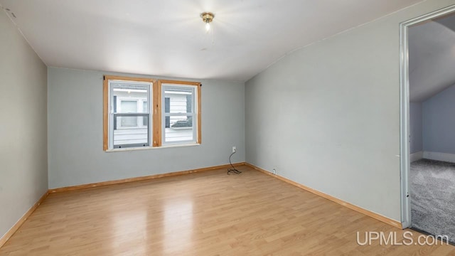 empty room with baseboards, vaulted ceiling, and wood finished floors