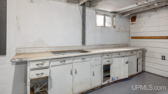 kitchen with light countertops, white cabinets, and concrete flooring