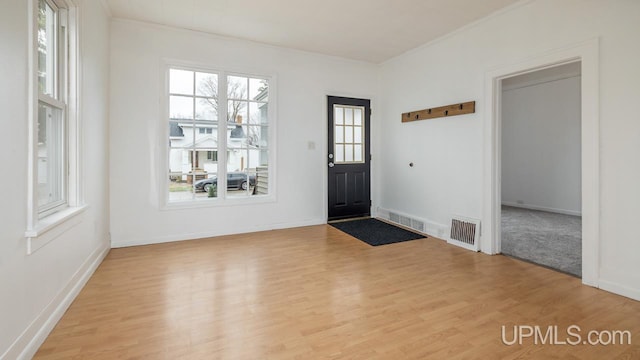 foyer entrance with crown molding, visible vents, and wood finished floors