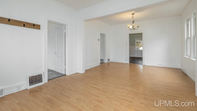 empty room featuring light wood-style floors, baseboards, an inviting chandelier, and visible vents
