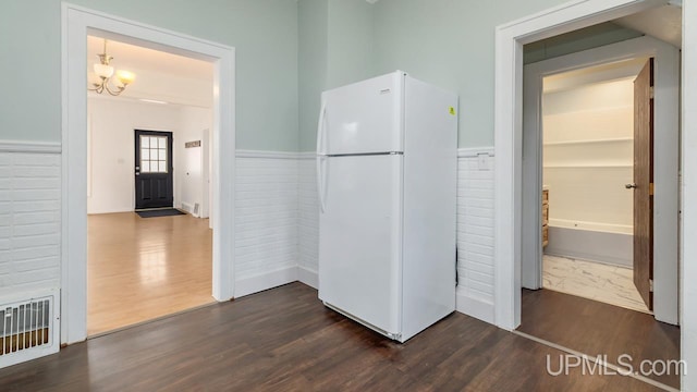 hallway with wainscoting, an inviting chandelier, dark wood-style floors, and visible vents