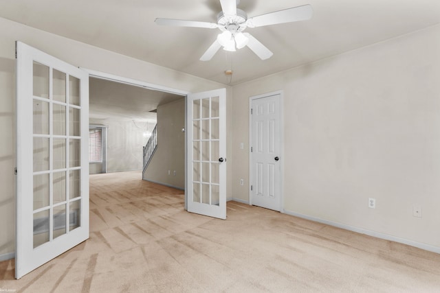 carpeted spare room featuring baseboards, ceiling fan, and french doors