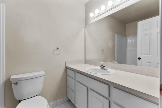 bathroom featuring toilet, tile patterned floors, baseboards, and vanity