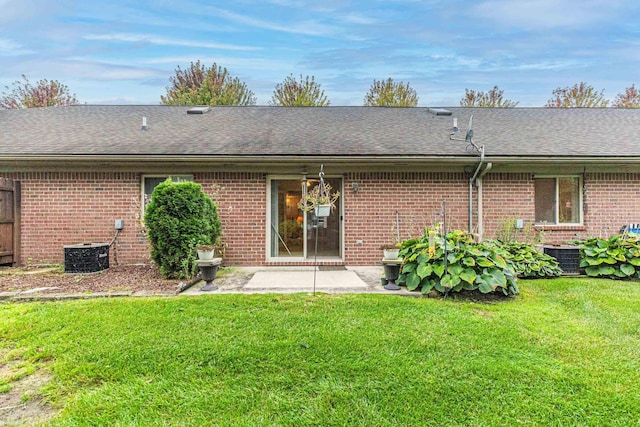 rear view of house with brick siding, a shingled roof, and a lawn