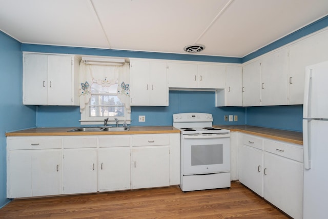 kitchen featuring visible vents, wood finished floors, white appliances, white cabinets, and a sink