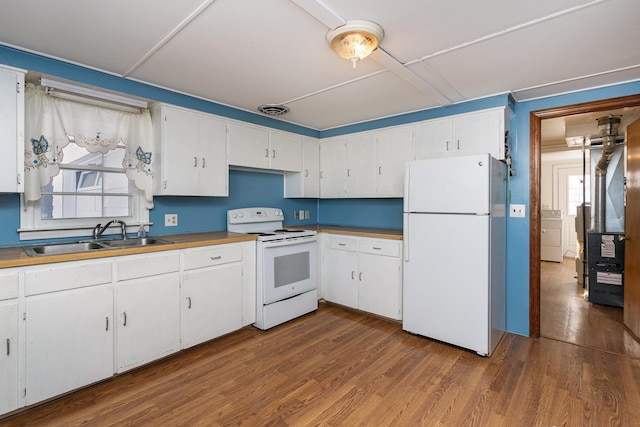 kitchen with dark wood-style flooring, a sink, white appliances, washer / dryer, and visible vents