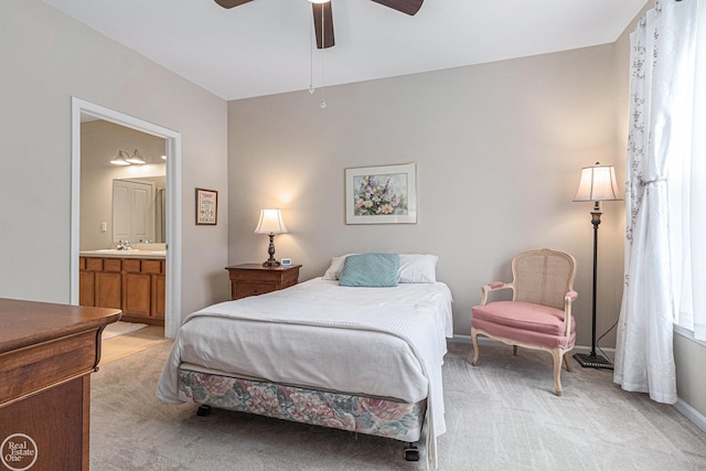 bedroom featuring baseboards, light colored carpet, a sink, and ensuite bath