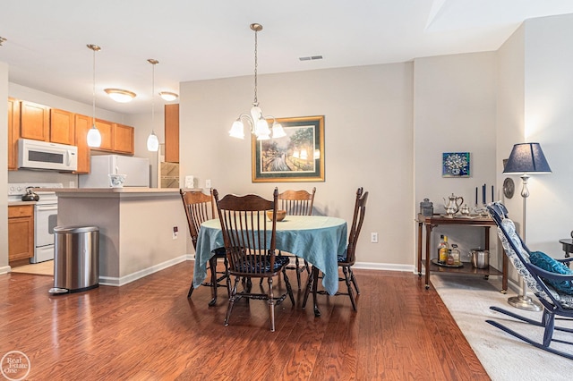 dining room featuring baseboards, a notable chandelier, visible vents, and wood finished floors
