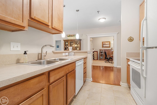 kitchen with a sink, white appliances, light countertops, decorative light fixtures, and light tile patterned floors