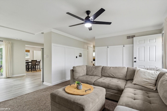 living room featuring light colored carpet, ceiling fan, visible vents, and baseboards