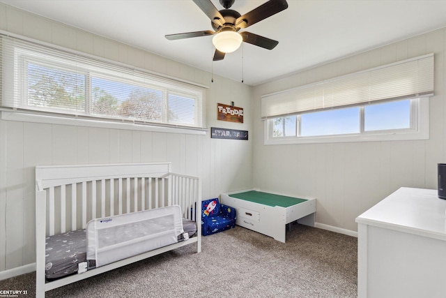 carpeted bedroom featuring ceiling fan and a nursery area